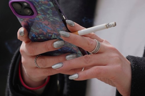 FILE - A woman smokes on a street in London on April 16, 2024. (AP Photo/Kin Cheung, File)