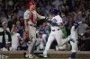 Chicago Cubs' Ian Happ (8), right, jogs by Philadelphia Phillies catcher J.T. Realmuto (10) to score on a single from Michael Busch (29) during the sixth inning of a baseball game Tuesday, April 21, 2026, in Chicago. (AP Photo/Erin Hooley)