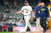 Milwaukee Brewers pitcher Brandon Woodruff, left, walks off the mound with Brewers head athletic trainer Brad Epstein after throwing a pitch during the second inning of a baseball game against the Arizona Diamondbacks, Thursday, April 30, 2026, in Milwaukee. (AP Photo/Kayla Wolf)