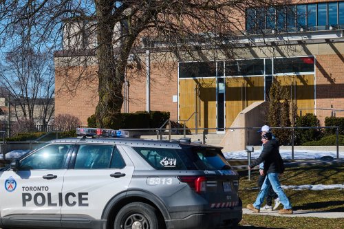 Pedestrians pass by a police car parked outside Shaarei Shomayim synagogue in Toronto, on Sunday, March 8, 2026. THE CANADIAN PRESS/Sammy Kogan