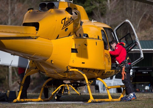 A member of North Shore Rescue retrieves equipment from a helicopter after landing at a base following a rescue operation in North Vancouver, B.C., Saturday, March 4, 2017. THE CANADIAN PRESS/Darryl Dyck