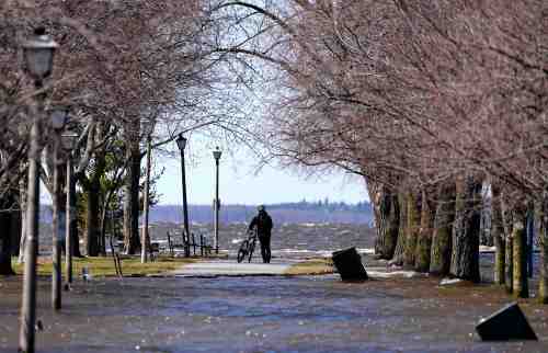 A cyclist walks their bike at Britannia Beach in Ottawa, as the Ottawa River floods onto a path, on Monday, April 20, 2026. THE CANADIAN PRESS/Justin Tang