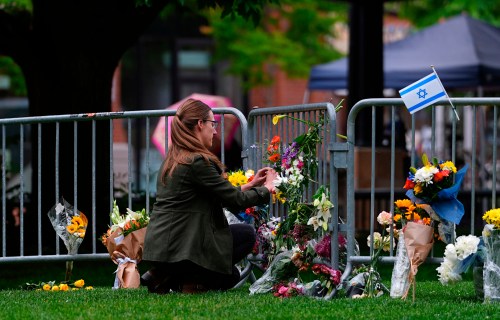 FILE - A woman places a bouquet of flowers at a makeshift memorial for victims of an attack outside of the Boulder County, Colo., courthouse Tuesday, June 3, 2025, in Boulder, Colo. (AP Photo/David Zalubowski, File)
