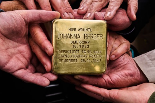 Relatives shows a photo a palm-sized brass Holocaust plaque reading 