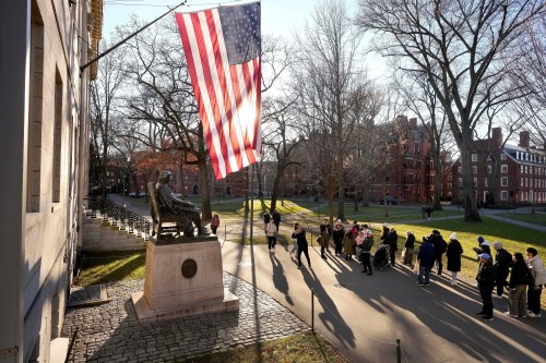 FILE - People take photos near a John Harvard statue, left, on the Harvard University campus, Jan. 2, 2024, in Cambridge, Mass. (AP Photo/Steven Senne, File)
