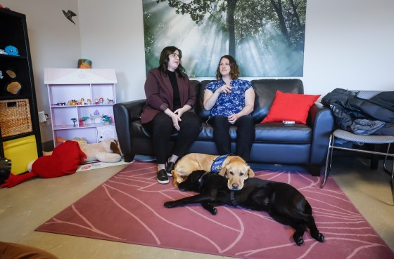 Victim service workers Carla Deeley, left, and Deanna Shaw, with their accredited facility dogs Bagel (blond) and Glossy (black) in the child victim family room at the Manitoba Law Courts. (John Woods / The Canadian Press files)