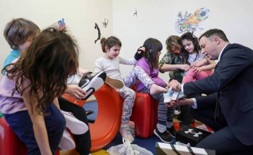Ruth Bonneville/Free Press
                                Finance Minister Adrien Sala helps a Grade 1 student, Emilie, put on her new shoes while handing out new shoes as part of a pre-budget event at Linwood Childcare Centre.