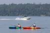 Kayakers paddle through the cool water of Clear Lake while a motorboat passes behind them in Riding Mountain National Park in 2023. Parks Canada announced Wednesday that motorboats will be allowed back on Clear Lake this season, but under new rules that will limit their use. (Tim Smith / The Brandon Sun files)
