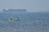 Two men sit in a small boat on the water as cargo ships are anchored in the background in the Strait of Hormuz off Bandar Abbas, Iran, Monday, May 4, 2026. (Amirhosein Khorgooi/ISNA via AP)