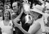 FILE - Lou Graham is flanked by his daughter, Louanne, left, and his wife, Patsy, as he carries the trophy after defeating John Mahaffey, Jr., in a playoff at the U.S. Open golf tournament, June 23, 1975, at Medinah Country Club in Medinah, Ill. (AP Photo/File)