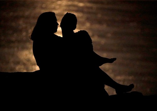 A couple is silhouetted against moonlight reflecting off the Missouri River in Kansas City, Mo. on June 27, 2018. THE CANADIAN PRESS/AP/Charlie Riedel
