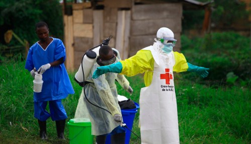 FILE - A health worker sprays disinfectant on his colleague after working at an Ebola treatment center in Beni, eastern Congo, Sept 9, 2018. (AP Photo/Al-hadji Kudra Maliro, File)