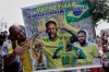 A fan poses with a poster of Brazilian soccer player Neymar, reading in Portuguese 