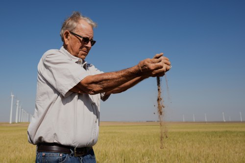 Farmer Orville Williams sifts powder dry soil as he checks the moisture in a drought-stressed wheat field Saturday, May 16, 2026, on his farm near Montezuma, Kan. (AP Photo/Charlie Riedel)