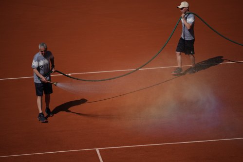 Stadium workers spray the court with water during the first round women's singles tennis match between Coco Gauff of the U.S. and Taylor Townsend of the U.S. at the French Open tennis tournament in Paris, Tuesday, May 26, 2026. (AP Photo/Christophe Ena)