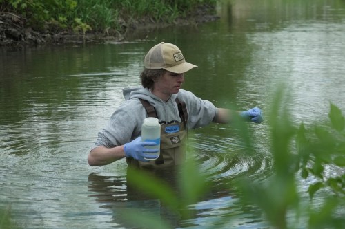 Drake University student Harrison Ziegler holds a bottle as he collects a water sample Wednesday, May 6, 2026, in Des Moines, Iowa. (AP Photo/Brittany Peterson)