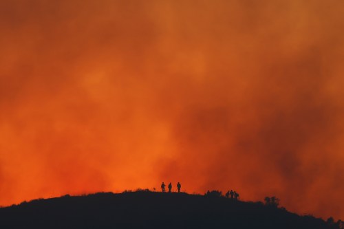 FILE - Firefighters are silhouetted amid an operation to control the Sandy Fire, May 19, 2026, in Simi Valley, Calif. (AP Photo/Caroline Brehman, File)
