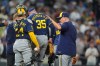 Milwaukee Brewers relief pitcher Brian Fitzpatrick (35) is helped off the mound by catcher William Contreras, front left, and manager Pat Murphy, right, after injuring himself while warming up in the seventh inning of a baseball game against the Colorado Rockies, Friday, June 5, 2026, in Denver. (AP Photo/David Zalubowski)