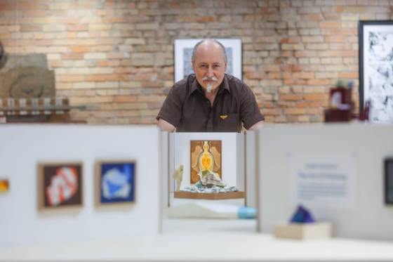 Robert Pasternak peeks over his Miniature Katie + Gunner Gallery gallery, which is at 1/12 scale and includes a 3D-printed model of Robert looking at his art. (Mike Deal / Free Press)