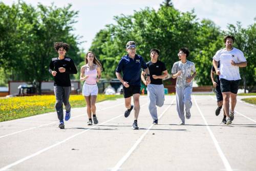 MIKAELA MACKENZIE / FREE PRESS
                                Coun. Brian Mayes runs with St. James Collegiate students and staff on the existing track after announcing funding to upgrade it on Thursday.