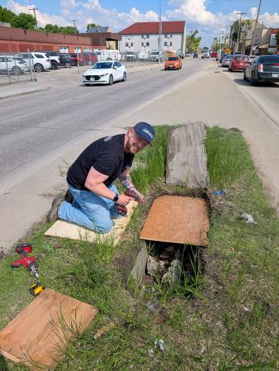 SUPPLIED
                                Robert Firman, operations manager with a nearby plumbing and heating company, provides a temporary fix to cover a hole on Logan Avenue near Patrick Street Thursday.