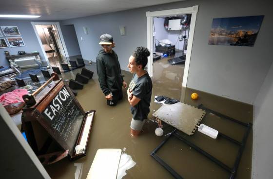 J'aime Killbery, her son Easton Killberry, and her partner Blair Mollberg work to salvage treasured family memorabilia as they wade through a basement flooded with a mixture of sewage and rainwater. (Ruth Bonneville / Free Press)