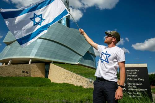 BROOK JONES/FREE PRESS
                                Jonathan K. waves an Israeli flag in front of the Canadian Museum for Human Rights during the protest, Friday.