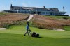 FILE - A man works on the 18th green in front of the clubhouse at Shinnecock Hills Golf Club in Southampton, N.Y., Monday, Sept. 15, 2025. (AP Photo/Seth Wenig, File