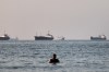 A person stands on shallow water as cargo and commercial vessels are anchored in the Strait of Hormuz off Bandar Abbas, Iran, Monday, June 8, 2026. (Amirhosein Khorgooi/ISNA via AP)
