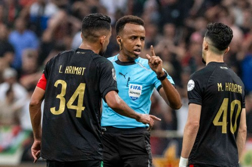 Referee Omar Artan, center, of Somalia, is confronted by players after calling a penalty kick during the CAF Champions League final soccer match between AS FAR Rabat and Mamelodi Sundowns, in Rabat, Morocco, Sunday, May 24, 2026. (AP Photo/Mosa'ab Elshamy)