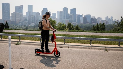 A haze of wildfire smoke from B.C. hangs over the downtown as man uses an electric scooter in Calgary on Thursday, July 15, 2021. THE CANADIAN PRESS/Jeff McIntosh