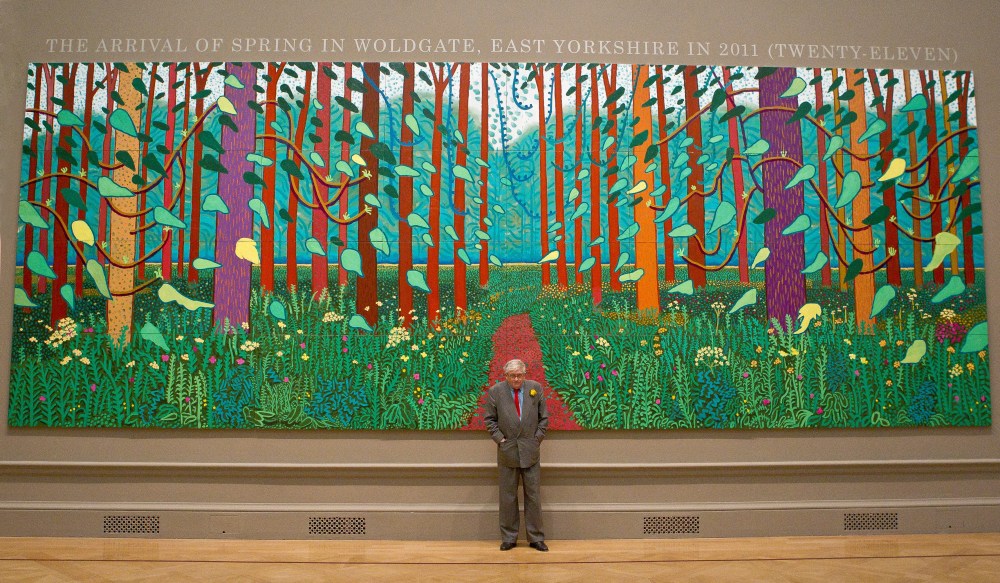FILE - British artist David Hockney stands before one of his paintings of the East Yorkshire landscape at The Royal Academy of Arts in Piccadilly, London, Monday, Jan. 16, 2012, ahead of his exhibition called 'A Bigger Picture'. (AP Photo/Joel Ryan)
