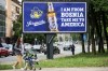 A woman walks past a billboard displaying lyrics from the Dubioza kolektiv song 