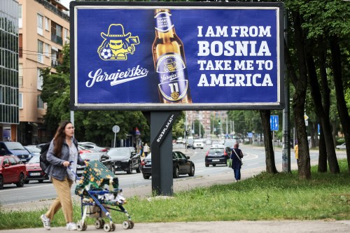 A woman walks past a billboard displaying lyrics from the Dubioza kolektiv song 