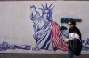 A woman walks past an anti-American mural on the wall of the former U.S. Embassy, now a museum, in Tehran, Iran, Friday, June 12, 2026. (AP Photo/Vahid Salemi)