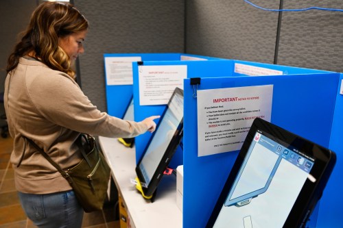 FILE- Courtney Parker votes on a new voting machine, in Dallas, Ga., Nov. 5, 2019. (AP Photo/Mike Stewart, File)