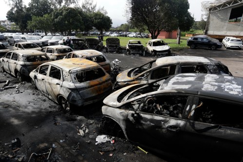 Burned vehicles fill a car dealership parking lot where, according to police, two helicopters collided in midair and crashed in Rio de Janeiro, Brazil, Sunday, June 14, 2026. (AP Photo/Bruna Prado)