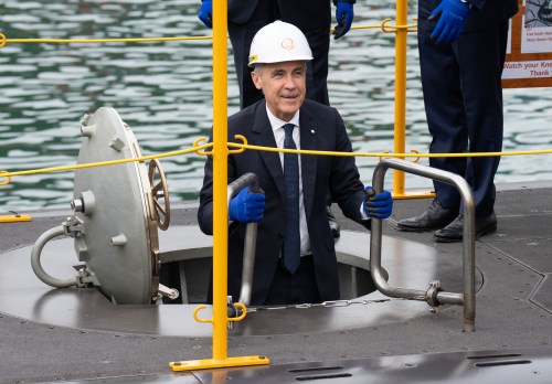 Prime Minister Mark Carney smiles as he climbs down a ladder into a submarine during a tour of the Hanwha Ocean Shipyard in Geoje Island, South Korea, on Thursday, Oct. 30, 2025. THE CANADIAN PRESS/Adrian Wyld