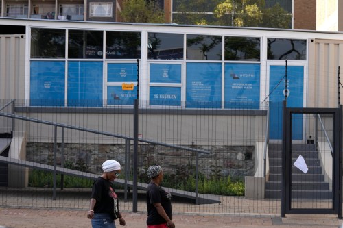FILE - Women walk past a closed clinic run by WITS Reproductive Health Institute (RHI) as a sign on the gate reads 