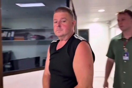 This image made from a video provided by TPBS, Australian identified as Simon Peter Carman, left, is led through a police station in Pattaya, Thailand, Sunday, June 28, 2026. (TPBS via AP)
