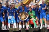 FILE - Chelsea team members, accompanied by President Donald Trump, celebrate with the championship trophy after the Club World Cup final soccer match between Chelsea and PSG in East Rutherford, N.J., July 13, 2025. (AP Photo/Jacquelyn Martin, File)