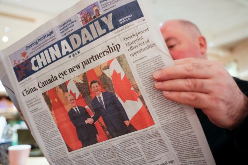 A picture of Prime Minister Mark Carney shaking hands with Chinese President Xi Jinping is seen on the cover of the weekend edition of the China Daily newspaper as a reader thumbs through the pages in Beijing, China on Saturday, Jan. 17, 2026. THE CANADIAN PRESS/Sean Kilpatrick
