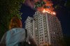 A woman looks at an apartment building burning after a Russian missile attack in Kyiv, Ukraine, Thursday, July 2, 2026. (AP Photo/Danylo Antoniuk)