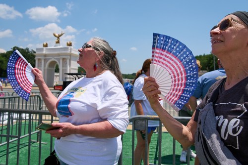 Mickelina Papotto, of Salem, Ore., left, and Lorie Odegaard, of Gaithersburg, Md., fan themselves while waiting in line for the ferris wheel at the Great American State Fair on the National Mall, Wednesday, July 1, 2026, in Washington. (AP Photo/Jacquelyn Martin)