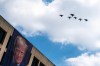 A flight of F-18s, F-35s and a F-22 fly past a picture of President Donald Trump hanging on the U.S. Department of Labor near the Great American State Fair on the National Mall, Friday, July 3, 2026, in Washington. (AP Photo/Nathan Howard)