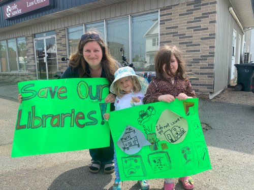 Krista Arsenault and her daughters Evie and Alice Arsenault pose with signs they made for a rally to save five rural libraries in their county that are slated to close next month, in Middleton, N.S., on Friday, June 5, 2026. THE CANADIAN PRESS/Lyndsay Armstrong