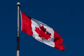 The Canadian flag is seen flying behind the national archives building in Ottawa Friday, Feb. 14, 2025, in Ottawa. THE CANADIAN PRESS/Adrian Wyld