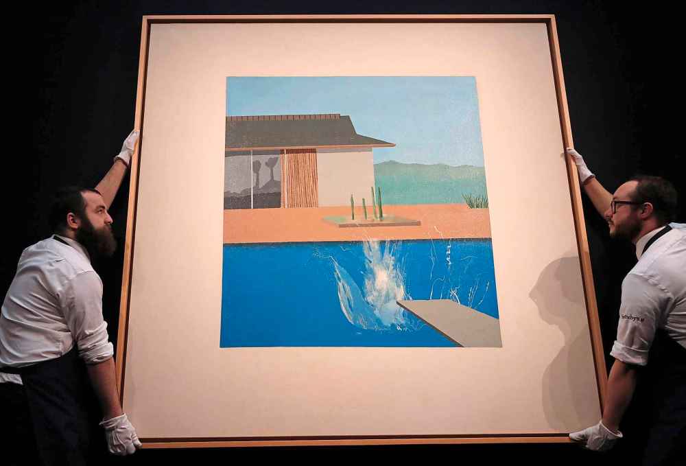 Two Sotheby's employees adjust David Hockney's painting 'The Splash' at Sotheby's contemporary Art sale preview in London, Friday, Feb. 7, 2020. (AP Photo/Frank Augstein)