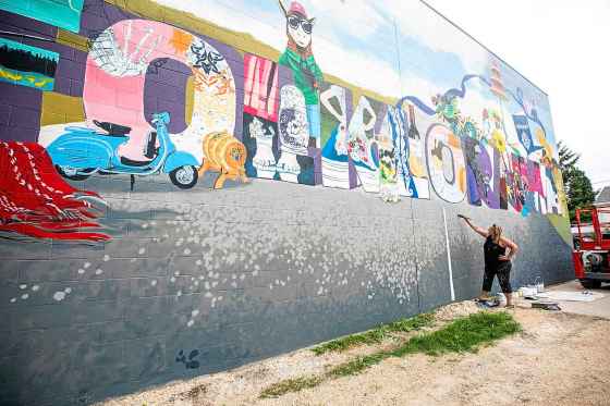 Muralist Mandy Van Leeuwen works on a new work commemorating Folklorama on Sargent Avenue earlier today. (Mikaela MacKenzie / Free Press)