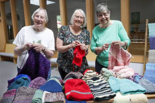 RUTH BONNEVILLE / FREE PRESS Nancy Sperling (from left), Elaine Lochhead and Lynnette Stamler of the Hooks and Needles knitting group with some of the wares inside Epiphany Lutheran Church.